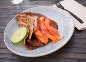 Salted salmon fillet with buckwheat pancakes and lime