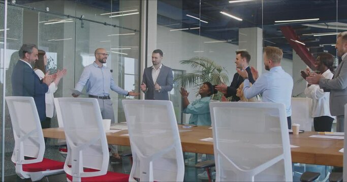 Chief is conducting a group meeting for the team of subordinates in the office. They are applauding to celebrate success, showcasing effective teamwork and leadership within the business.