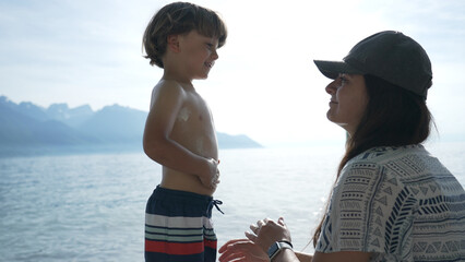 Mother Applying Sunscreen to Joyful Son on a Sunny Day at Mountain Lake
