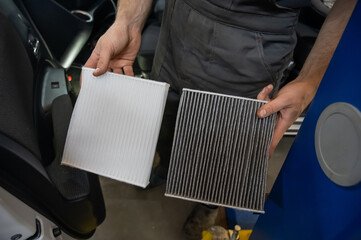 Mechanic holding old and new cabin air car filters. 