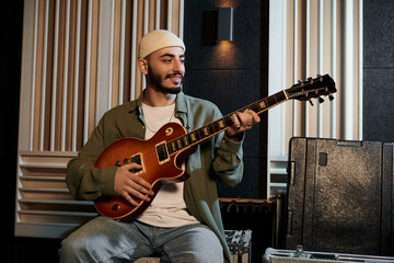 Obraz premium A musician strums a guitar in a recording studio during a music band rehearsal.