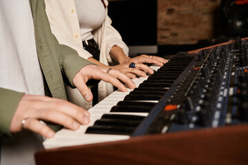 Obraz premium Two individuals performing music on a keyboard in a recording studio for a band rehearsal session.