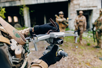 Fototapeta premium Soldier fpv operator attaches bomb to drone to strike enemy positions. Concept use of modern robot in military operations
