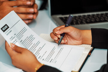 Human resources department manager reads CV resume document of an employee candidate at interview room. Job application, recruit and labor hiring concept. uds
