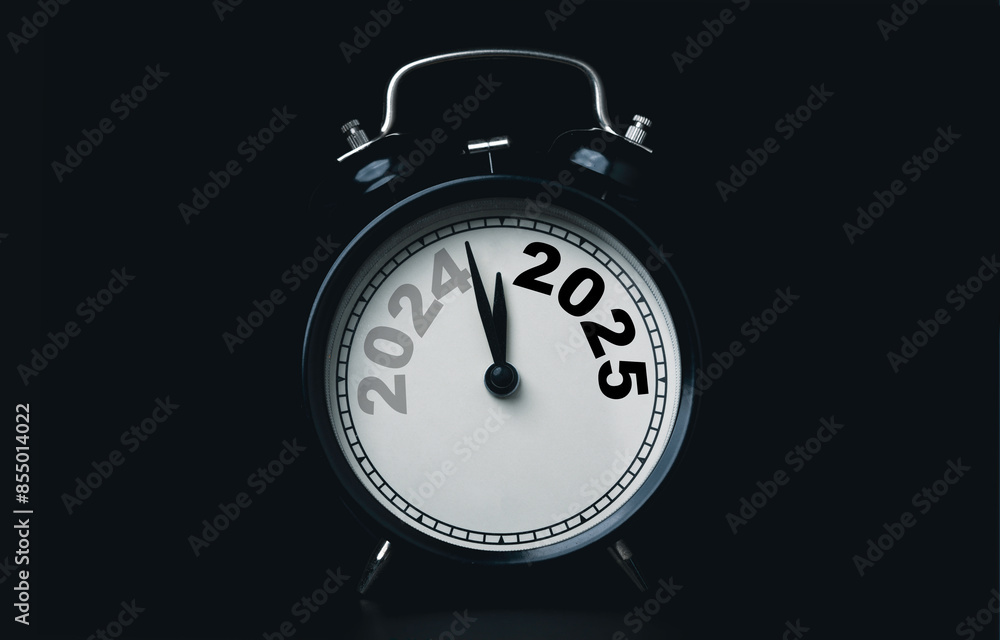 Aufkleber 2024 and 2025 on black alarm clock on dark background with copy space for preparation of merry chris