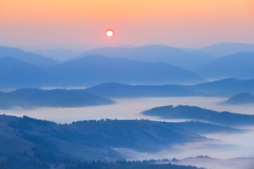 mountain chain silhouette in dense mist at the sunrise