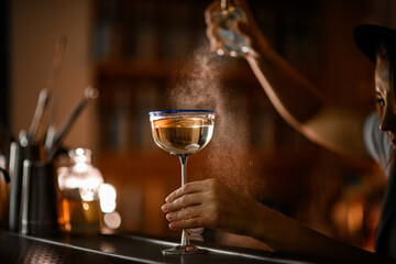 Glass with a tall metal stem is on the bar, filled with a bubbly cocktail