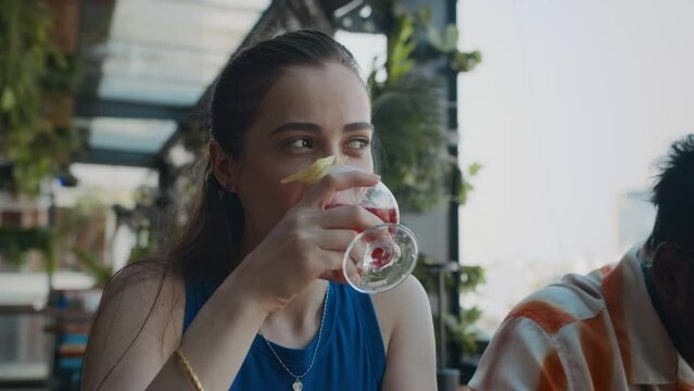 Tilt up shot of young Caucasian woman hanging out with cocktails while meeting with her friends in local cafe