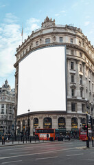 Obraz premium Large Blank Billboard on Classic European Building in the Heart of a Historic City with Red Double Decker Buses and Clear Blue Sky Perfect for Advertisements and Urban Landscape Photography