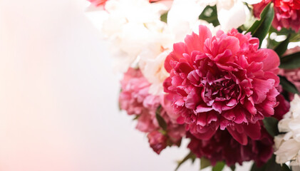 Beautiful peonies of different colors in a glass vase on the windowsill.