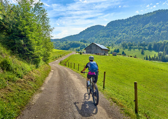 pretty senior woman riding her electric mountain bike on the mountains above Oberstaufen with...