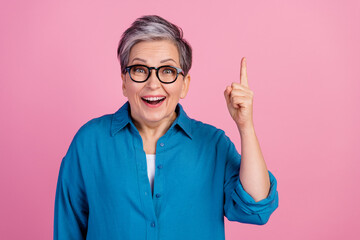 Photo portrait of attractive senior woman point up eureka dressed stylish blue clothes isolated on...