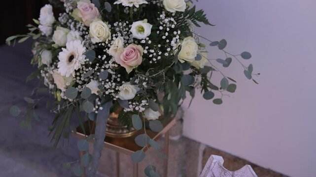 Elegant floral arrangement with roses and greenery in a church setting.