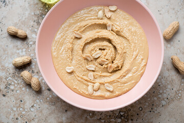Roseate bowl with peanut butter, horizontal shot on a beige granite background, high angle view, middle closeup