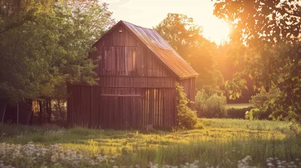 Poster de jardin  Warm light illuminating an old wooden barn during sunset in the countryside  © AkuAku