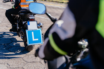 A man is riding a motorcycle with a blue plate with letter L