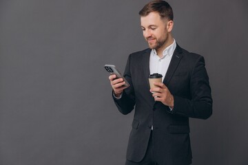 Happy business man smiling businessman professional wearing suit holding cell phone using smartphone mobile app online standing isolated on gray background