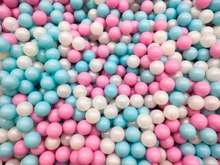 Colorful plastic balls in a playground ball pit. The balls have pink, blue, and white colors. Flat lay, overhead, or top view shot.
