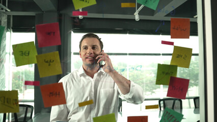 Professional businessman making phone call to customers while looking at marketing strategy idea...