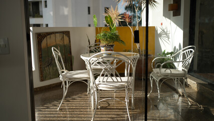 Sunlit Outdoor Patio Setting with White Wrought Iron Furniture and Exotic Plants