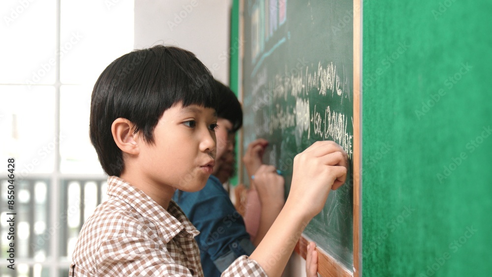Poster side view of asian boy writing engineering prompt and programing system while standing blackboard wi