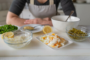 Woman in the kitchen with ingredients for making a tartar sauce.
