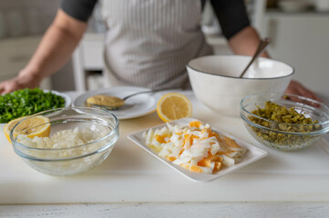 Woman in the kitchen with ingredients for making a tartar sauce.