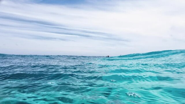 POV watch waves Surface half underwater caribbean Sea With bubbles and Sky Reflections, Los Roques