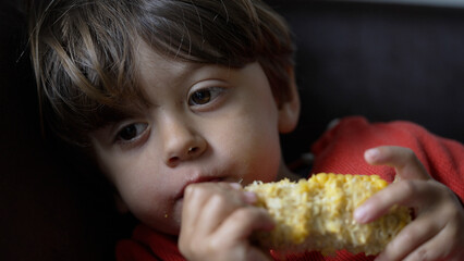 Young Boy Enjoying Fresh Corn on the Cob - Intimate Close-Up Indoors