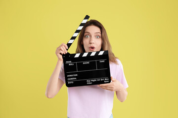 Making movie. Surprised woman with clapperboard on yellow background