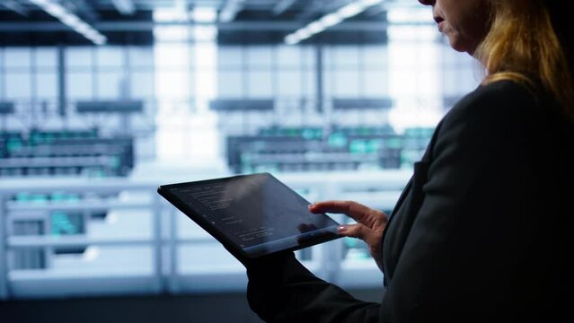 System administrator doing annual checkup using tablet to prolong data center equipment life span. Close up shot of IT expert in server hub monitoring supercomputers using digital device, camera B