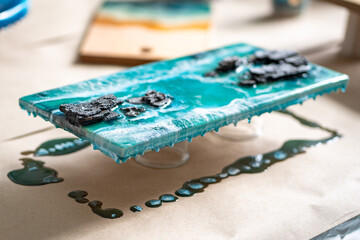 Closeup of finished product drying, lying on stand of glasses, epoxy resin dripping onto bedding,...