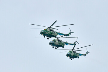 Three Russian military helicopters armed with missiles flies in blue sky, airborne mission of...