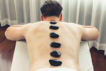 Hot stone massage at spa salon in luxury resort with day light serenity ambient, blissful man...