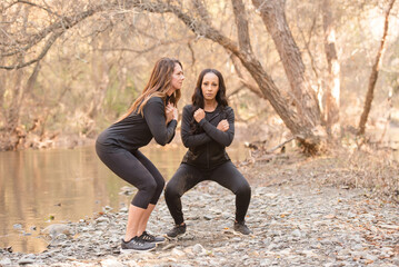 Women working out by a river squatting