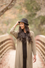 Women on a bridge holding her hat and wearing a coat