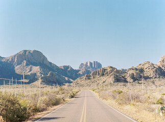 A road in the center of the frame trailing off to the Chisos Mou