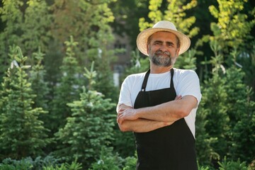 Obraz premium Arms crossed, standing. Senior gardener is at work at daytime