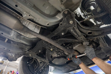 A mechanic unscrews a car's oil filter. 