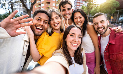 Multicultural friends taking selfie with smart mobile phone outside