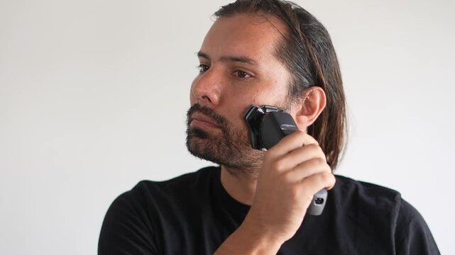 Latino man trimming beard and mustache with electric razor, Shaving gel
