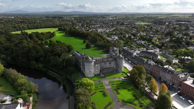 Kilkenny Castle, County Kilkenny, Ireland, September 2023. Drone orbits from the River Nore across the elegant formal gardens with the Blackstairs Mountains of County Carlow in the distance.