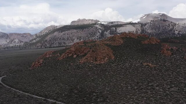Snow-capped mountains with rugged red hills in the foreground, and diverse landscape of the Eastern Sierra. Inyo National Forest, California, USA