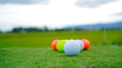 Golf ball on green grass in the evening golf course with sunshine background.
