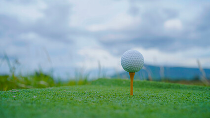 Golf ball on tee in a beautiful golf course with morning sunshine.