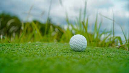 Golf ball on green grass in the evening golf course with sunshine background.