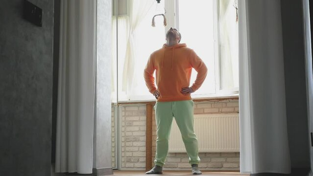 A man performs an exercise tilting his head to the right and left. Warm-up during training. Young athlete warming up.