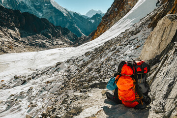 Nepalese Sherpa guide porter carry heavy backpack sit relax rests on viewpoint trekking Everest...