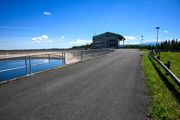 Water reservoir with dam wall and building on a sunny day with blue sky