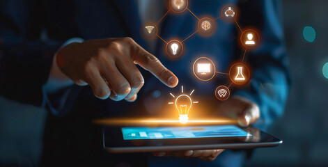 Close up of a businessman using a tablet with business icons of a glowing light bulb, money symbol, and house symbol on the screen